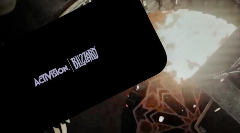 logo of ''Activision Blizzard'' is displayed on a mobile phone screen in front of a computer