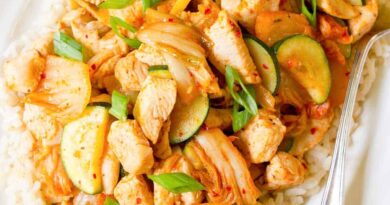 Kimchi chicken stir fry and rice on a white plate.