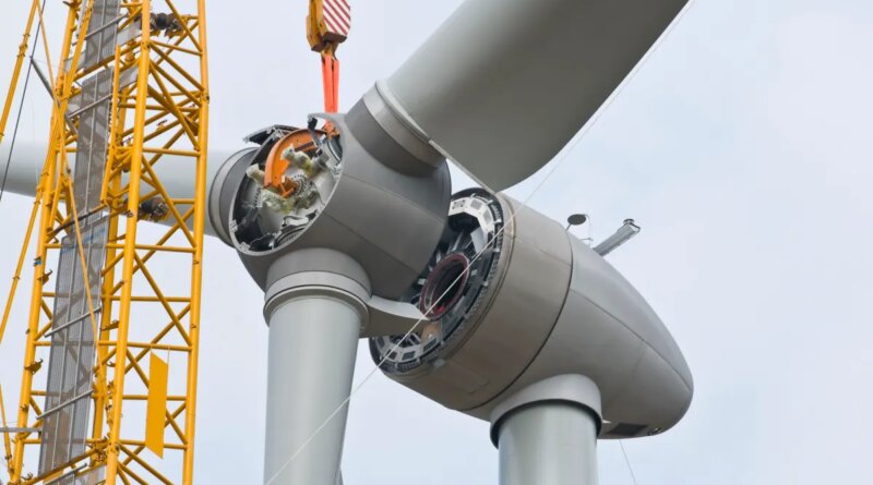 A crane positions the rotor of a wind turbine during construction.