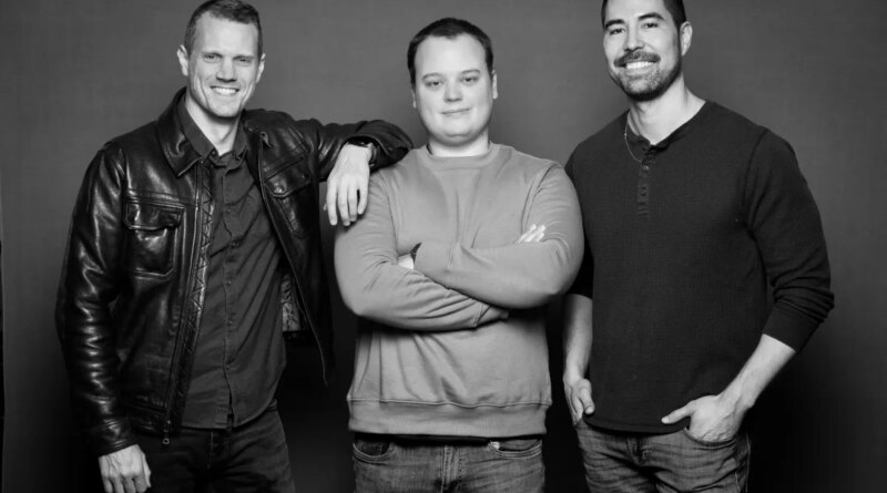 A grayscale photo of three men standing against a neutral background.