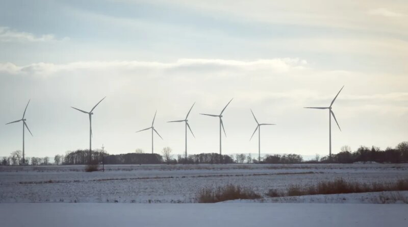 Wind turbines stand across open fields near a railway line in northern Poland, on January 10, 2026.