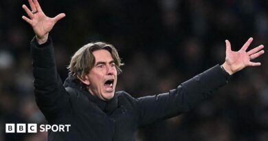 Tottenham head coach Thomas Frank, in a black coat, has his arms and hands outstretched in an animated gesture
