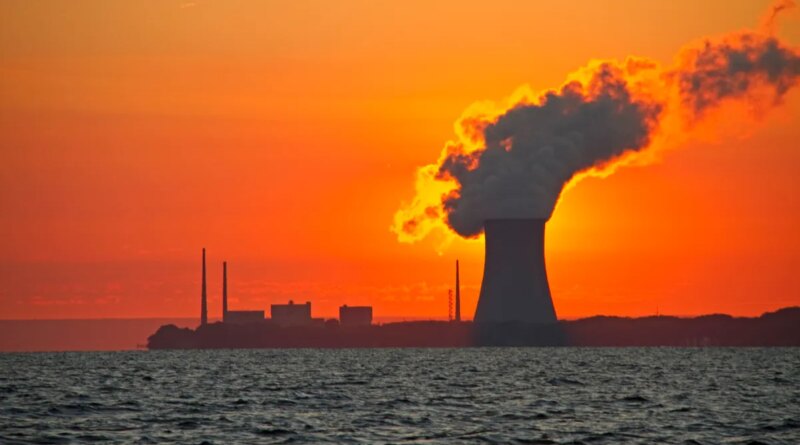 The sun rises behind a nuclear power plant cooling tower.