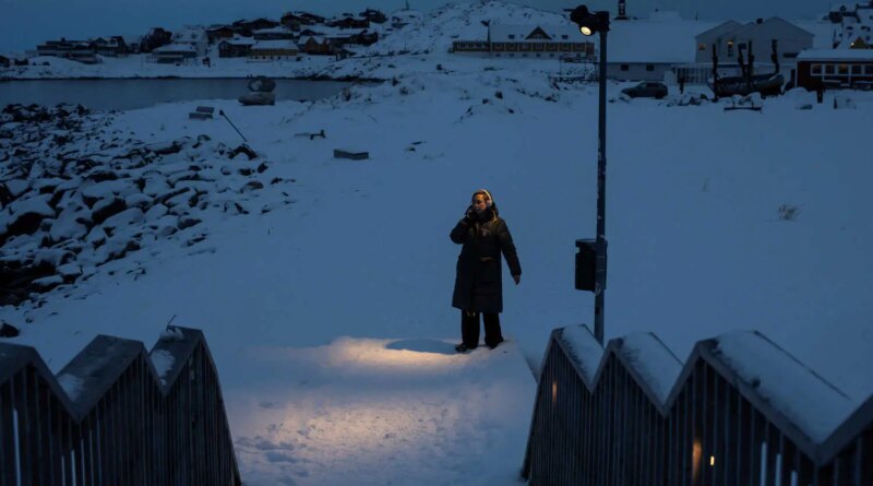 A person stands in the snow beneath a lantern, with a harbor in the distance and a snow-covered staircase in the foreground.