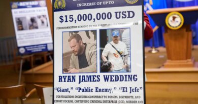 A poster with two photos of a person wanted by the F.B.I. is shown near a lectern.