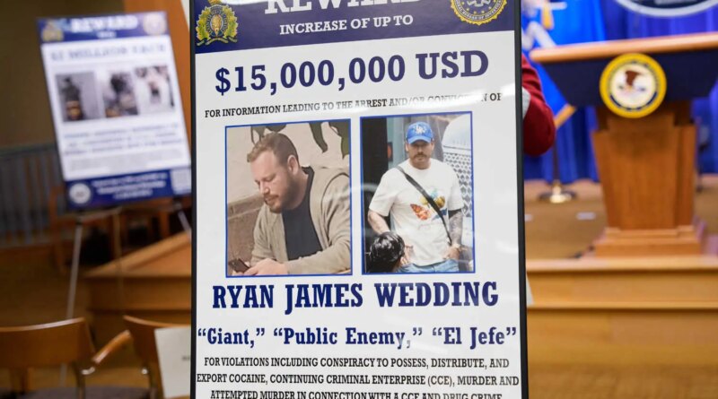 A poster with two photos of a person wanted by the F.B.I. is shown near a lectern.