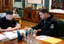 Volodymyr Zelensky and Kyrylo Budanov sit at a desk in an official office, reviewing documents together.