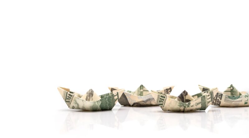 row of paper ships from dollar banknotes
