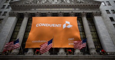 Conduent Inc. signage is displayed as American flags fly outside of the New York Stock Exchange (NYSE) in New York, U.S., on Tuesday, Jan. 3, 2017. U.S. stocks rose Tuesday, pointing to the biggest gain in a month for Wall Street's first session of the new year, helped by a string of robust economic data from China and Europe. Photographer: Michael Nagle/Bloomberg via Getty Images