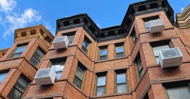 Heat pumps hang on the outside of an apartment building.
