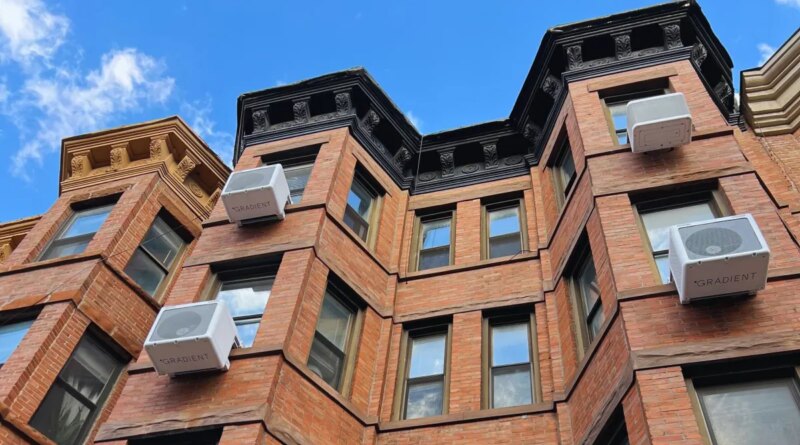 Heat pumps hang on the outside of an apartment building.