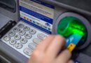 a close-up photo of a person punching in their PIN on an ATM in a wall.