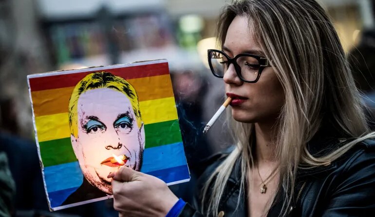 FILE PHOTO: A woman lights a cigarette placed in a placard depicting Hungary's Prime Minister Viktor Orban, during a demonstration, after the Hungarian parliament passed a law that bans LGBTQ+ communities from holding the annual Pride march and allows a broader constraint on freedom of assembly, in Budapest, Hungary, March 25, 2025. REUTERS/Marton Monus/File Photo
