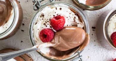 Chocolate mousse in jars with whipped cream and raspberries.