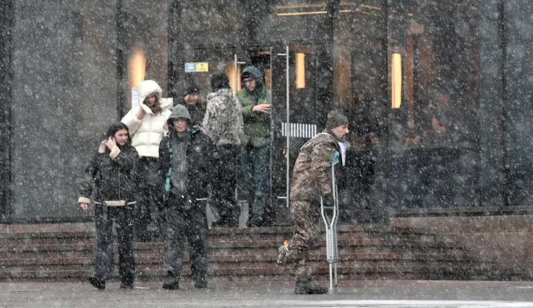 A wounded Ukrainian serviceman walks in a street in Kyiv during snow fall on February 15, 2026, amid Russian invasion in Ukraine. (Photo by Sergei SUPINSKY / AFP)