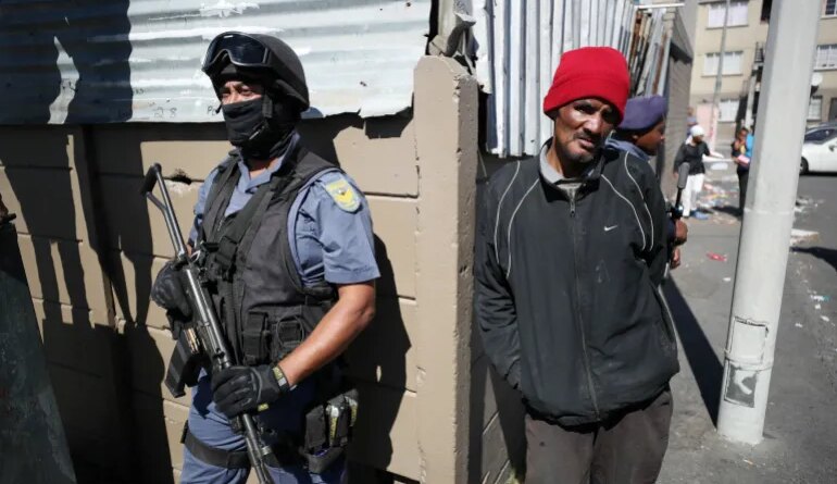 Residents look on as police stand guard while South African President Cyril Ramaphosa visits crime ridden Hanover Park to launch a new Anti-Gang Unit, in Cape Town, South Africa November 2, 2018. REUTERS/Mike Hutchings