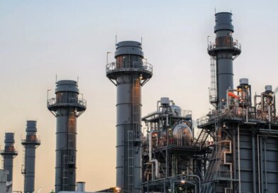 Natural gas power plant smoke stacks stand against a twilight sky.