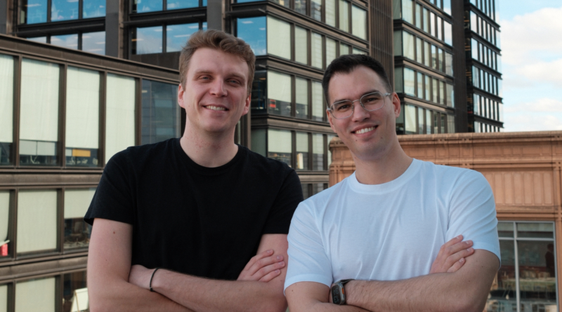 Two men stand on a rooftop, crossing their arms