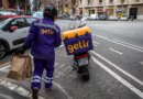 Getir delivery driver holding grocery bags and walking to Getir delivery bike