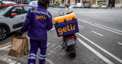 Getir delivery driver holding grocery bags and walking to Getir delivery bike