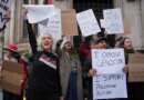 Protesters hold signs that read "I OPPOSE GENOCIDE" and "I SUPPORT PALESTINE ACTION." Many people have their mouths open as if shouting.