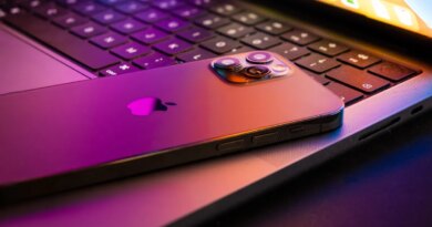 MacBook pro 2021 half open with Iphone 13 lit by retina display