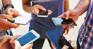 5 friends with smartphones, close up.