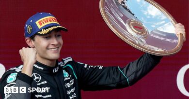 Mercedes' George Russell clenches his fist and lifts up the winner's trophy on the podium after the Australian Grand Prix
