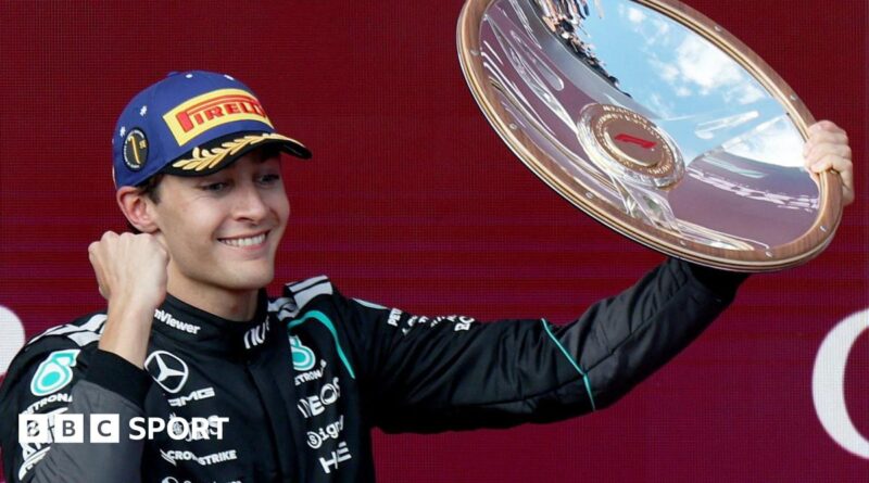 Mercedes' George Russell clenches his fist and lifts up the winner's trophy on the podium after the Australian Grand Prix