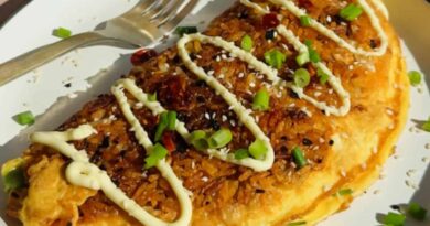 Omelette in a pan topped with chopped carrots, edamame, corn, and fresh herbs, shown in natural sunlight.