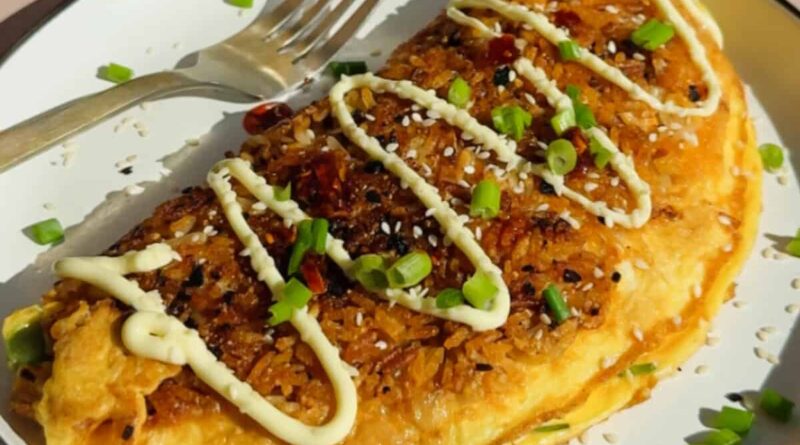 Omelette in a pan topped with chopped carrots, edamame, corn, and fresh herbs, shown in natural sunlight.