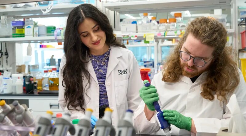 Two scientists pipette chemicals in a lab.