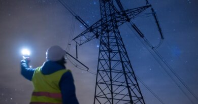 High-voltage engineer working on power lines at night.