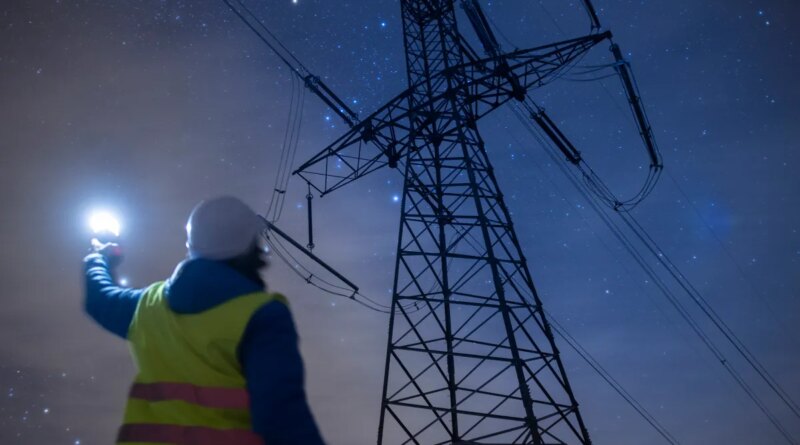 High-voltage engineer working on power lines at night.