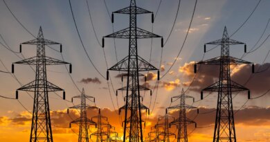 The sun sets behind transmission lines.