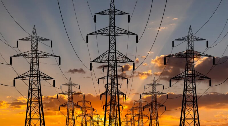 The sun sets behind transmission lines.