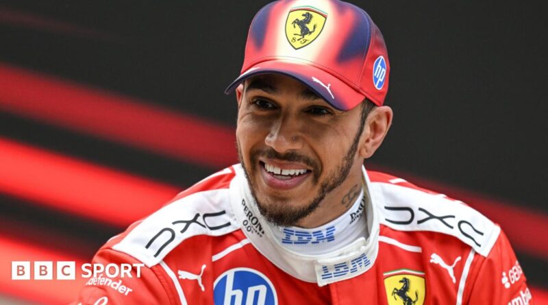 A smiling Lewis Hamilton wearing a Ferrari cap and race overall after he finished third in the Chinese Grand Prix