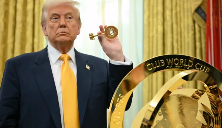 Trump holds up a key in front of the FIFA Club Cup Trophy
