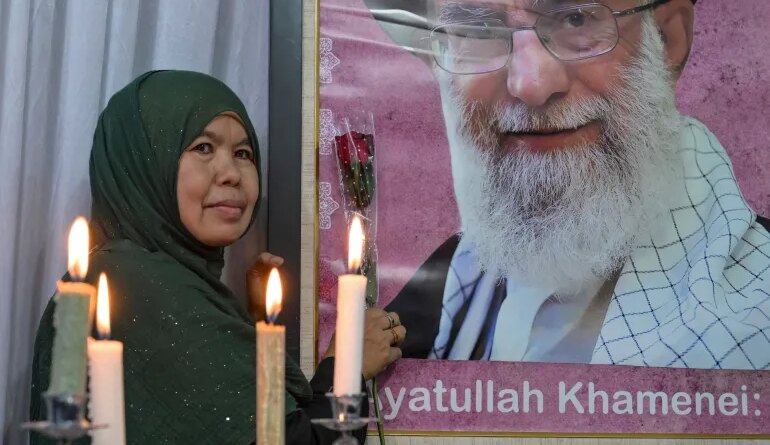 A mourner poses next to a portrait of Iranian supreme leader Ayatollah Ali Khamenei, who was killed amid US-Israel strikes, during the signing of a petition committing to international justice values, held at the Iranian Ambassador's residence in Jakarta on March 5, 2026. (Photo by BAY ISMOYO / AFP)
