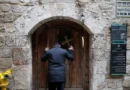 Palestinian Christian who is popular for being the Santa Claus of the city, holds a cross and a palm frond while standing at the doors of the Church of the Holy Sepulchre after finding them locked