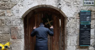 Palestinian Christian who is popular for being the Santa Claus of the city, holds a cross and a palm frond while standing at the doors of the Church of the Holy Sepulchre after finding them locked