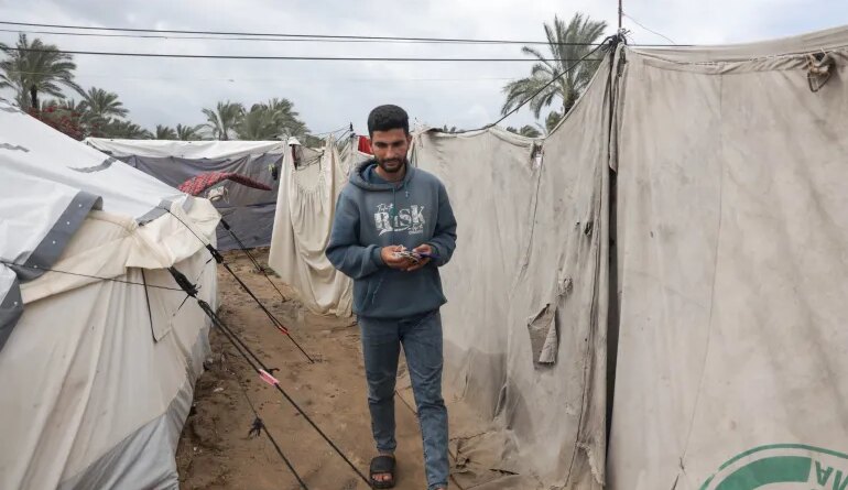 Abdel Karim Salman heads daily to the charging station to charge his phone and his wife’s phone, which they use as a source of light in their tent throughout the night [Abdelhakim Abu Riash/ Al Jazeera]