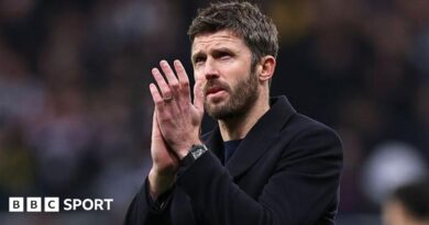 Michael Carrick, in a dark coat, applauds Manchester United fans