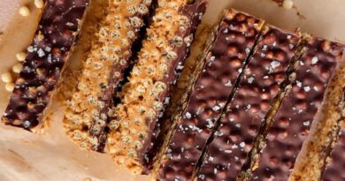 Rectangular chocolate and peanut butter crispy bars with a sprinkle of sea salt, arranged on parchment paper.