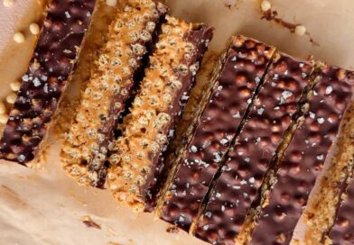 Rectangular chocolate and peanut butter crispy bars with a sprinkle of sea salt, arranged on parchment paper.