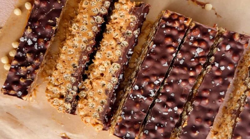 Rectangular chocolate and peanut butter crispy bars with a sprinkle of sea salt, arranged on parchment paper.
