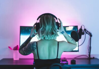 Image of a woman putting on headphones in front of a computer screen and microphone.