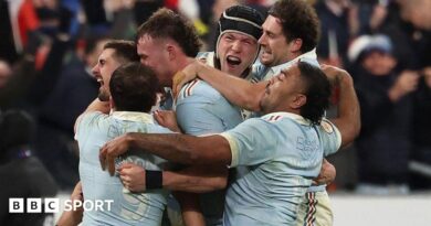 Thomas Ramos is mobbed by his France team-mates after landing the final kick to claim victory