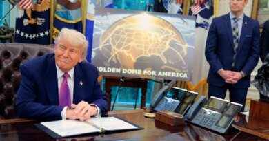Golden Dome missile program placard with Trump sitting at desk