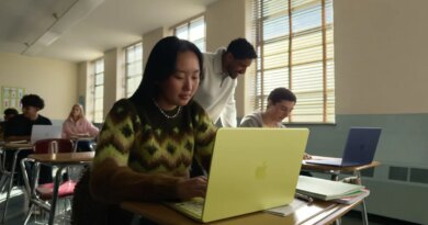 young woman seated at a classroom desk using a MacBook Neo